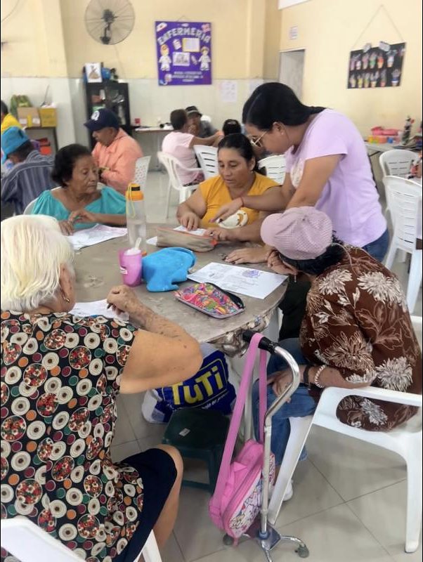 Una técnica acompaña a adultos mayores en una actividad de lectura
